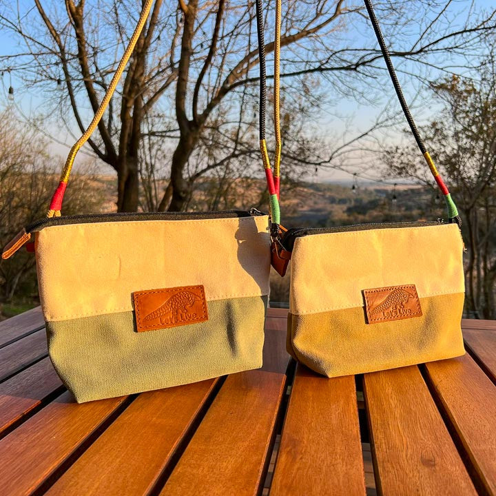 Two beige hand bags with leather Let's Live Pangolin patches hanging