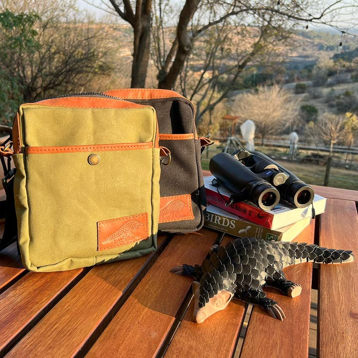 Green Canvas Binocular bag with brown leather trim. Pangolin in foreground