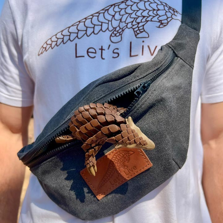 Person wearing a grey fanny pack with a Let's Live pangolin inside