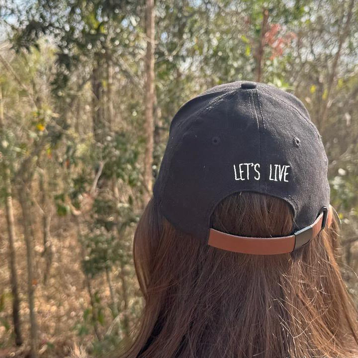 Lady wearing a black flexi / sport cap with 'LET'S LIVE' text