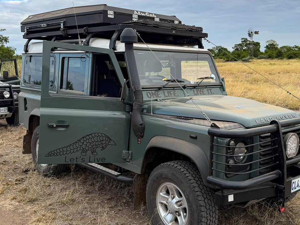Let's Live Pangolin Decal on driver-side door of green Land Rover Defender