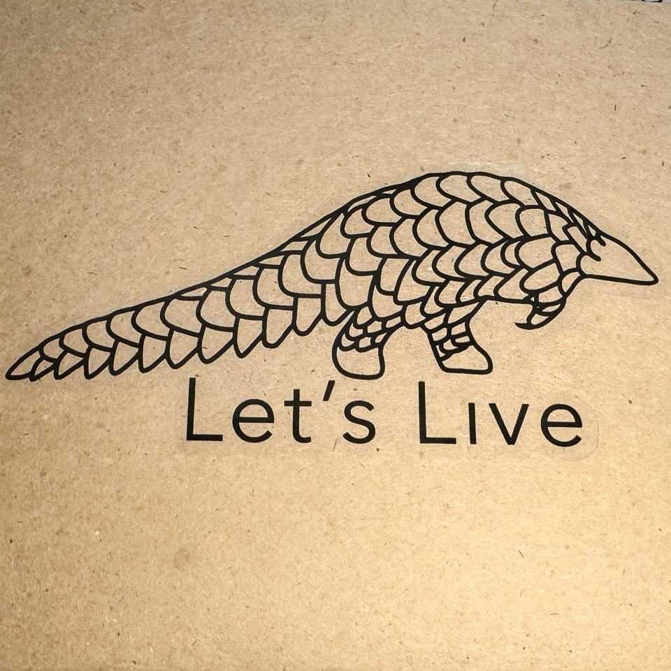 Let's live pangolin sticker with clear backing on a brown background