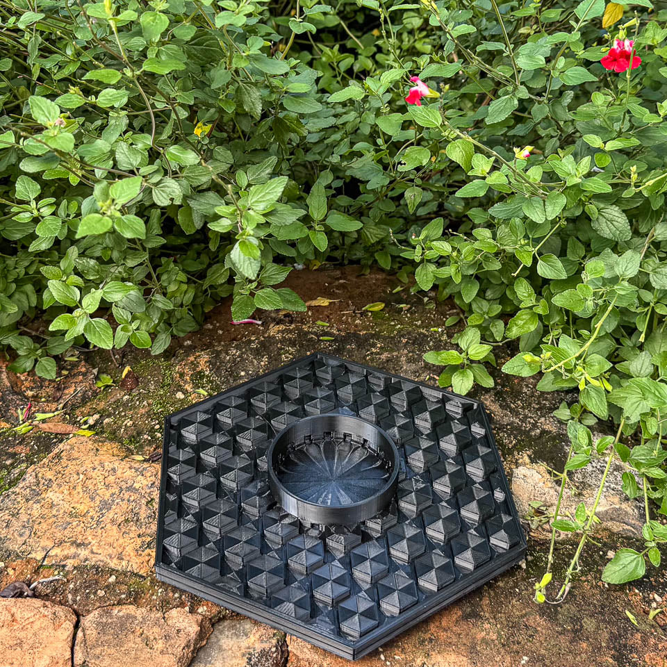 A hexagonal black plastic bee water tray to prevent drowning