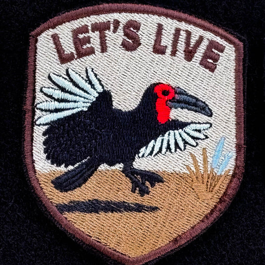 Embroidered patch with a Ground Hornbill flying and 'LET'S LIVE' text