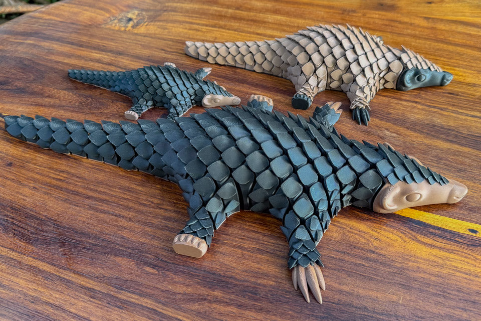Three pangolin-shaped toys of various sizes
