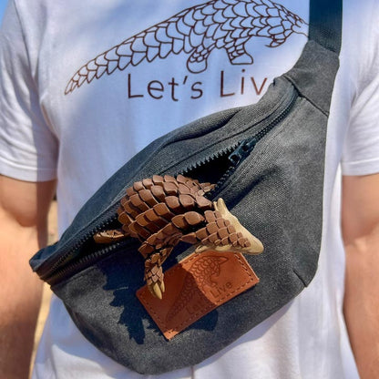 Person wearing a grey fanny pack with a Let's Live pangolin inside