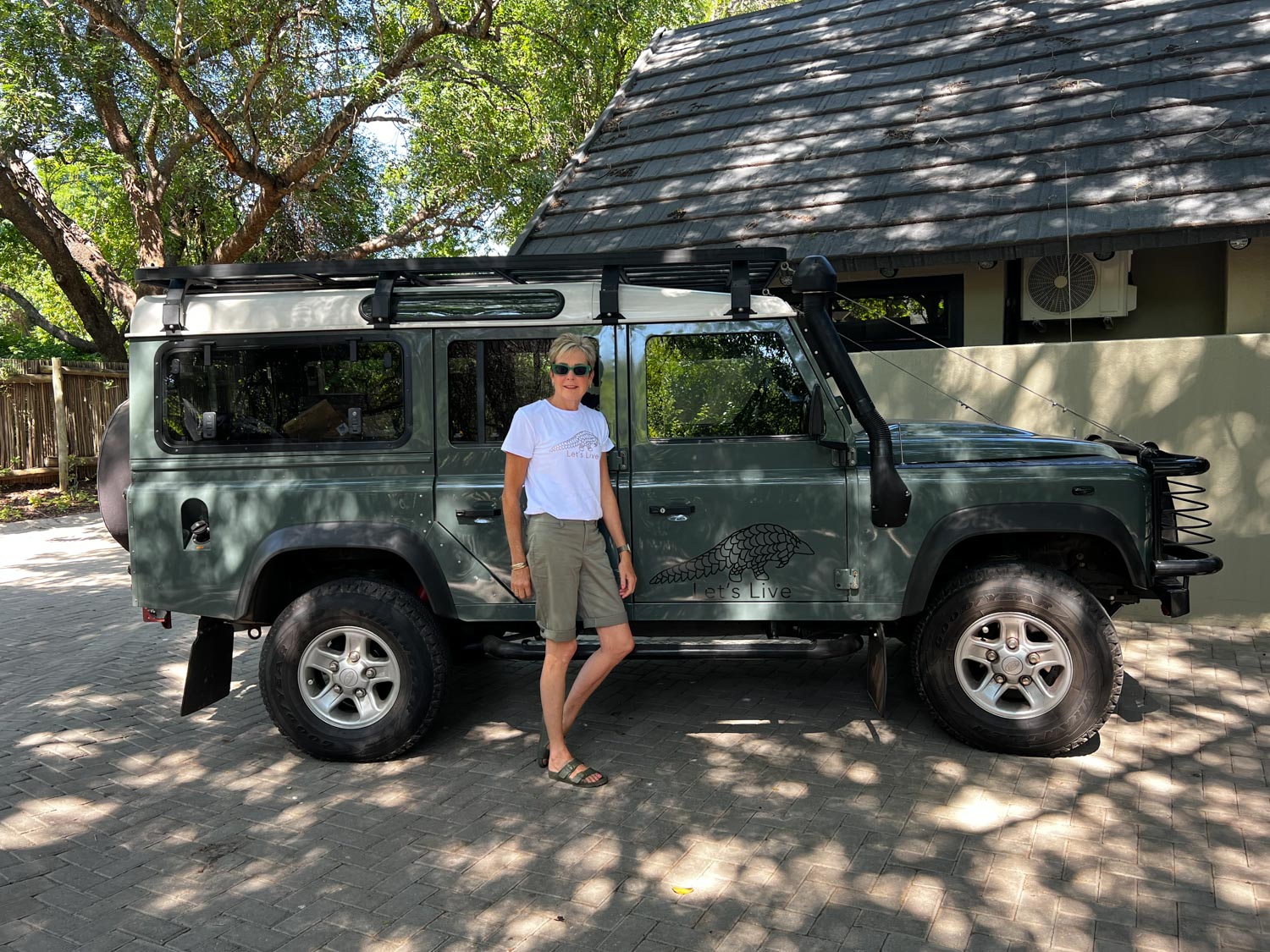 Lets Live Pangolin Shirt being worn by woman posing next to a Land Rover Defender