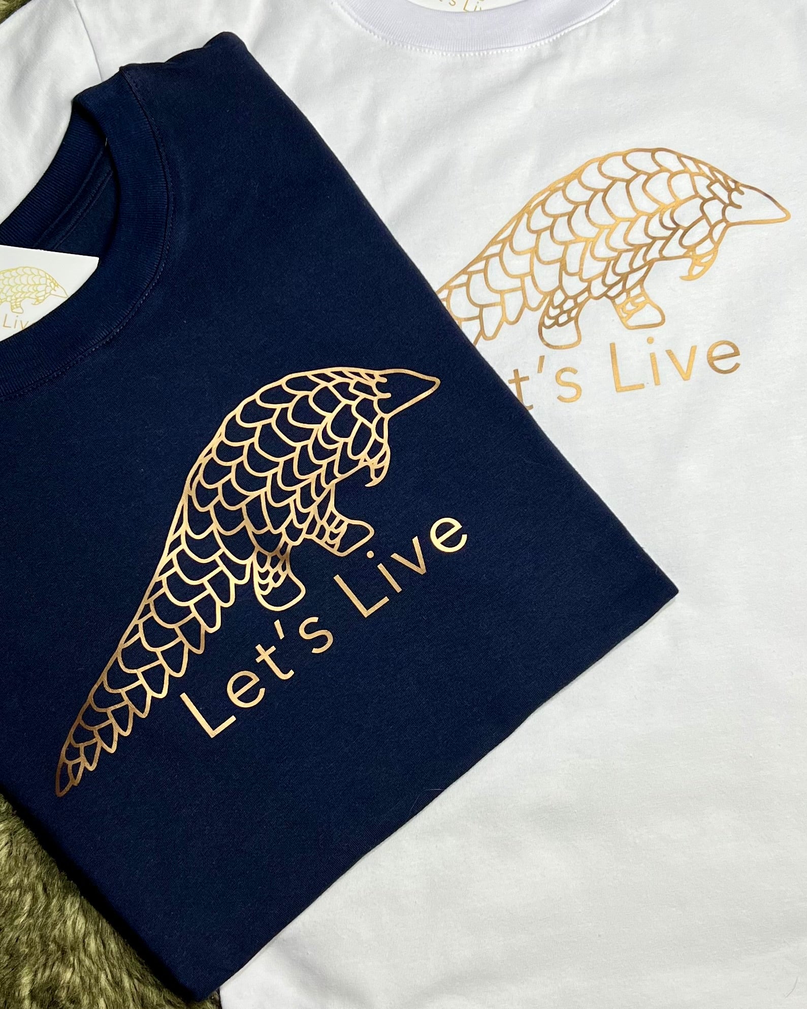 Lets Live Pangolin Navy Tshirts folded over white Shirt