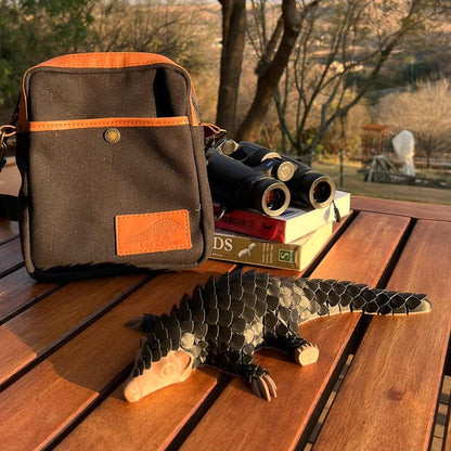 Black Canvas Binocular bag with brown leather trim. Pangolin in foreground